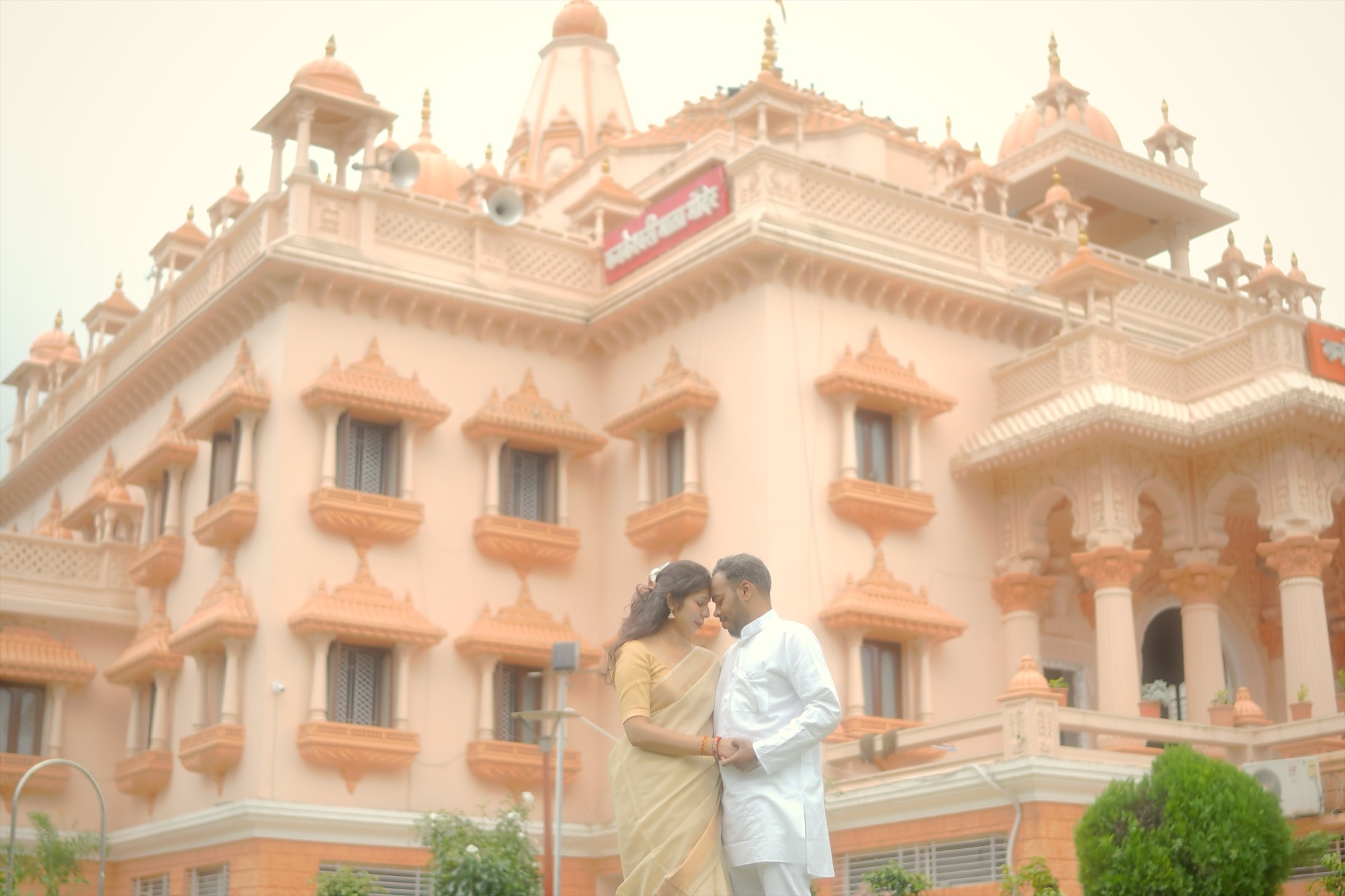 Suyash and Astha, foreheads touching, in front of a palace